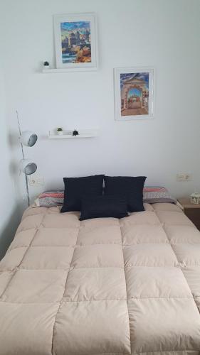 a bed in a bedroom with a white wall at apartamento gaditano in Cádiz