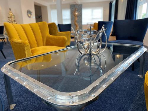 a glass coffee table with yellow chairs on a room at Rooms At Babbacombe in Torquay