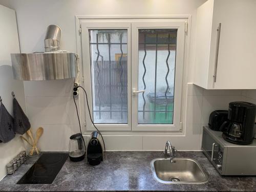 eine Küche mit einem Waschbecken und einem Fenster in der Unterkunft Charmant appartement - PARIS 18 in Paris