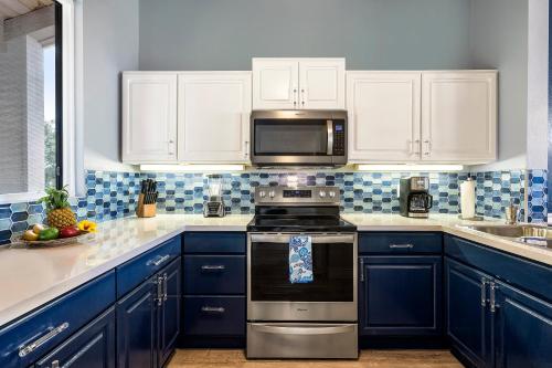 a kitchen with blue cabinets and a stove top oven at Keauhou Kona Surf Racquet 9303 in Kailua-Kona