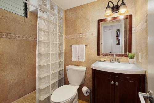 een badkamer met een toilet, een wastafel en een spiegel bij Poipu Shores B202 in Koloa