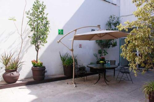 a patio with a table with an umbrella and potted plants at Hotel Río Puebla Centro in Puebla