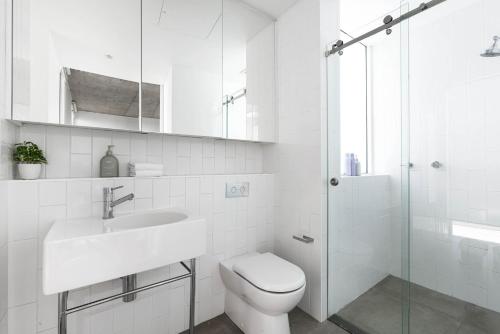 a white bathroom with a toilet and a sink at The Chromatic Apartments by Urban Rest in Sydney