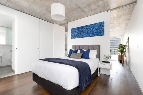 a bedroom with a large bed with blue pillows at The Chromatic Apartments by Urban Rest in Sydney