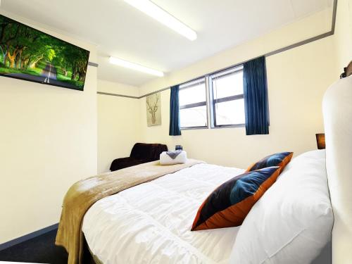 a bedroom with a large white bed and a window at Rarakau Lodge in Tuatapere