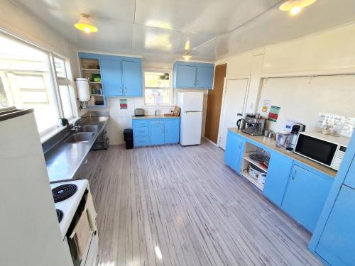 a kitchen with blue cabinets and a wooden floor at Rarakau Lodge in Tuatapere