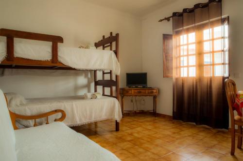 a room with two bunk beds and a television at Apartamento Rosa in Porto Covo