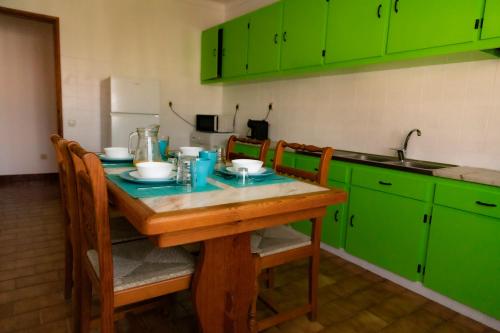 a kitchen with green cabinets and a wooden table at Apartamento Rosa in Porto Covo