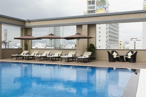 a swimming pool with chairs and umbrellas on a building at Muong Thanh Grand Cua Lo Hotel in Cửa Lô
