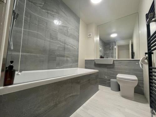 a bathroom with a tub and a toilet and a sink at Stylish Seaside home with King beds and parking in Scarborough