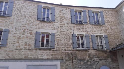 un vieux bâtiment en briques avec des fenêtres bleues à volets dans l'établissement Chez Ma Petite Reine 1, à Pontoise