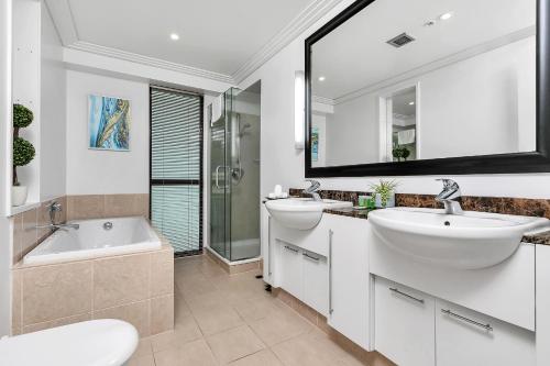 uma casa de banho com 2 lavatórios, uma banheira e um espelho. em Glamorous Getaway - Heart of the Viaduct 'Quays' em Auckland