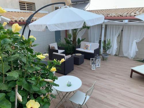 eine Terrasse mit einem Tisch, einem Sonnenschirm und Stühlen in der Unterkunft Holiday Home Sicily Talia che Bed-du in Punta Braccetto