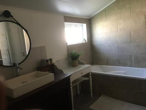 une salle de bain avec un lavabo, une baignoire et un miroir dans l'établissement Maison jardin 3 ch centre ville Bassin Arcachon, à Audenge