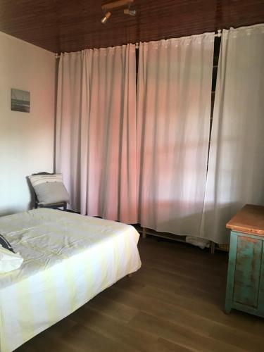 une chambre avec un lit et une fenêtre avec des rideaux dans l'établissement Maison jardin 3 ch centre ville Bassin Arcachon, à Audenge