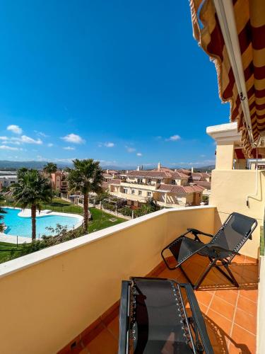 balcone con 2 sedie e piscina di Casa Baviera Golf & Beach a Caleta de Velez