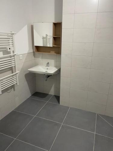 La salle de bains est pourvue d'un lavabo et de carrelage. dans l'établissement Logement du centre equestre du val d'or, à Fontaine-sur-Ay