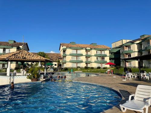 einen Pool in einem Hotel mit Stühlen und einem Gebäude in der Unterkunft Flat E311 - Aldeia das águas in Barra do Piraí