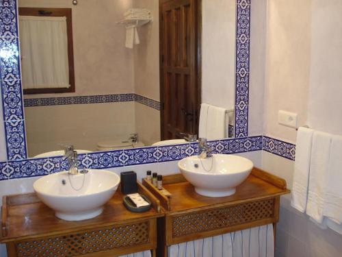 
a bathroom with two sinks and a mirror at Hotel Cortijo de Salia in Alcaucín
