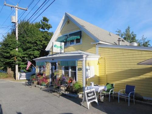 a yellow house with chairs and a sign in front of it at 24 Sea Mist Lane Chatham Cape Cod - - The Sea Mist in South Chatham