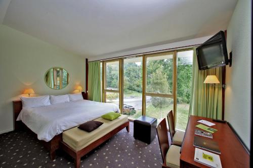 a hotel room with a bed and a large window at Logis des Lacs d'Halco in Hagetmau