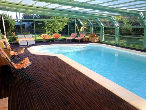 een zwembad op een houten terras naast een huis bij Chambre d'hôte avec piscine couverte in Coulaines