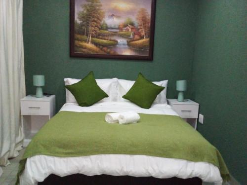 1 dormitorio verde con 1 cama con 2 toallas en Kwa-Ntokozo Guesthouse-Tweefontein, en Tweefontein