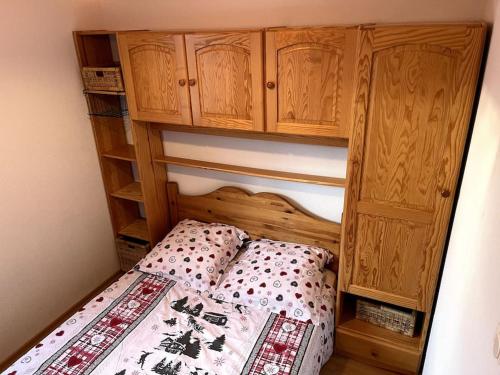 a small bedroom with a bed and a wooden cabinet at Le petit bonhomme de neige in Gérardmer