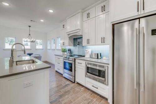 a kitchen with white cabinets and a stainless steel refrigerator at Stylish townhome near AT&T Stadium, Globe Life, Six Flags & More in Arlington