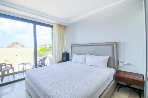 um quarto com uma cama e uma grande janela em One Paralia 405 em Playa del Carmen