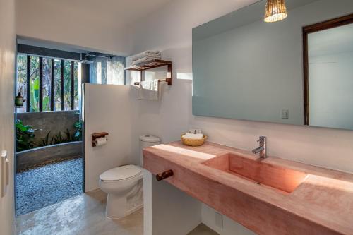 a bathroom with a sink and a toilet and a mirror at Casa Kuaa in Brisas de Zicatela