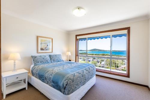 a bedroom with a bed and a large window at 10 Garuwa Street - Fabulous Fingal Bay water views in Fingal Bay
