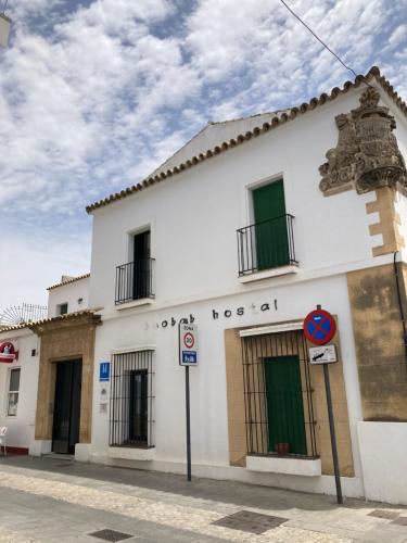 a white building with green doors on a street at Hostal Baobab in El Puerto de Santa María