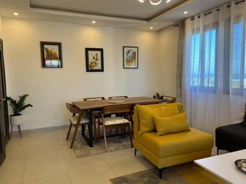 a living room with a wooden table and a yellow chair at Superb Urban Oasis in Almadies in Dakar