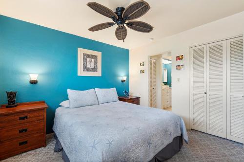 a blue bedroom with a bed and a ceiling fan at Casa De Emdeko 222 in Kailua-Kona