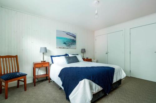 a bedroom with a blue and white bed and a chair at The Yellow Door Inverloch in Inverloch