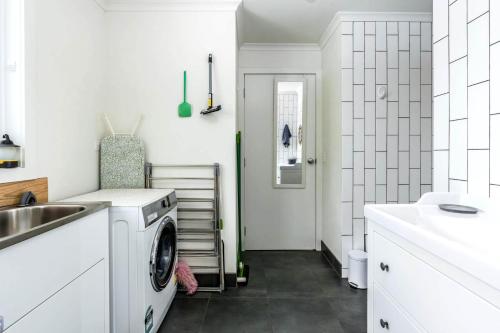 a white laundry room with a sink and a washing machine at The Yellow Door Inverloch in Inverloch