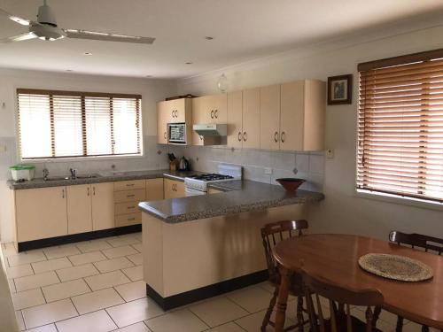 a kitchen with white cabinets and a wooden table at Unit 2, 36 Sunderland Street Evans Head in Evans Head