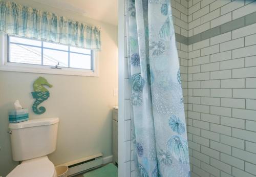 a bathroom with a toilet and a blue shower curtain at 168 #8 North Shore Boulevard Tidal View #8 East Sandwich - Cape in East Sandwich