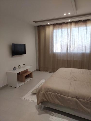 1 dormitorio con 1 cama y TV de pantalla plana en Appartement Residence Essayedi Sousse, en Port El Kantaoui