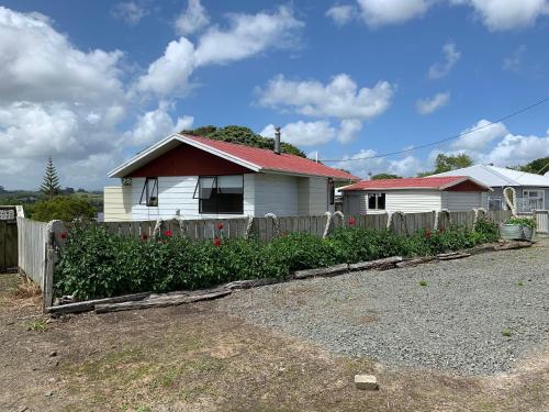 a house with a fence in front of a yard at Peaceful Riverfront cottage in small northland town in Te Kopuru