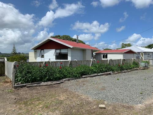 ein Haus mit einem Zaun vor einem Hof in der Unterkunft Peaceful Riverfront cottage in small northland town in Te Kopuru