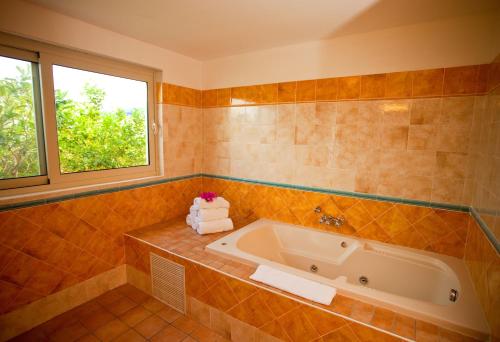 a bathroom with a tub and a window at Royal Islander Club Resort La Terrasse in Lowlands