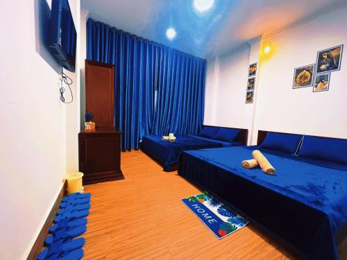 a room with two beds and a couch and a television at Nhan Tay Hostel in Can Tho