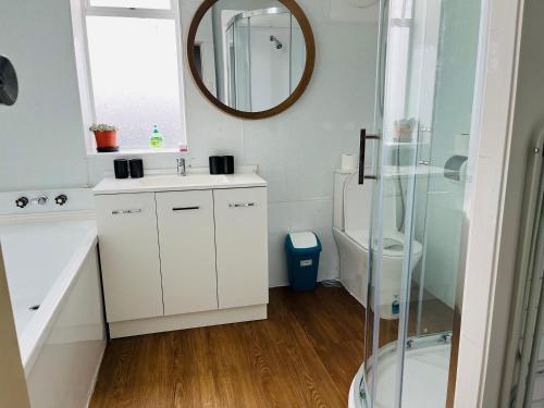 a bathroom with a white sink and a mirror at Modern Upstairs Apartment in Dunedin Central in Dunedin