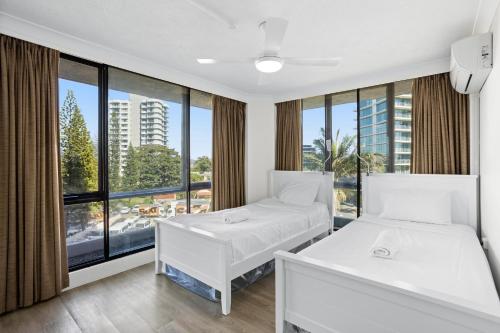 Dos camas en una habitación con una gran ventana. en Genesis Apartments by Gold Coast Premium, en Gold Coast