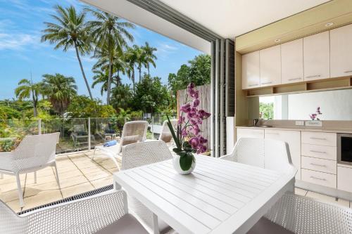 eine Küche und ein Esszimmer mit einem weißen Tisch und Stühlen in der Unterkunft Seascape Holidays at Club Tropical in Port Douglas