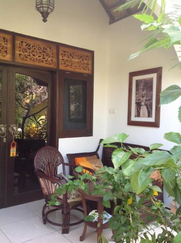 a porch with a chair and a table and a plant at Gili Nyepi in Gili Trawangan