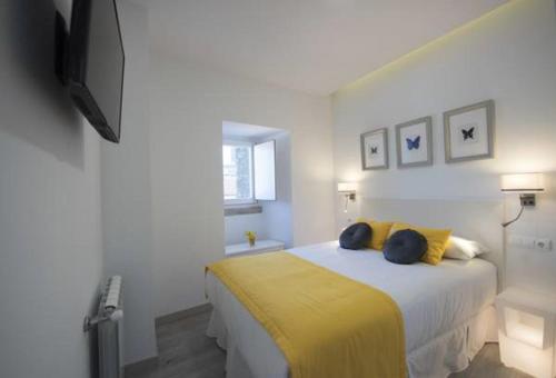 um quarto com uma cama com um cobertor amarelo em Bolboreta Dreams Apartamentos Turísticos em Santiago de Compostela