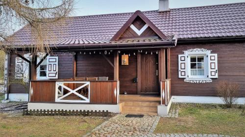 a wooden house with a front porch and a door at Podlaski Zakątek in Bereżyszcze